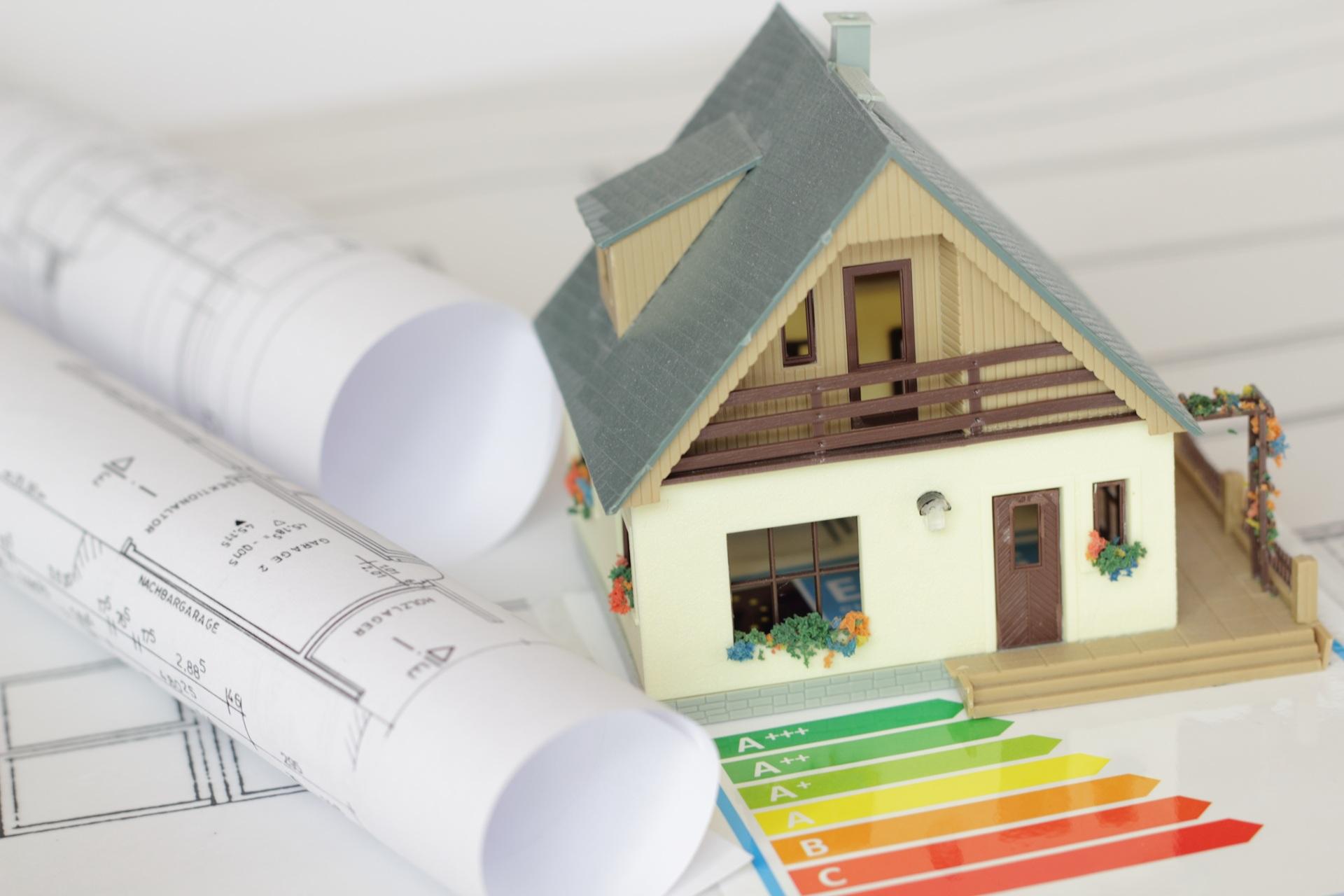 Hausmodell mit Energieeffizienzskala und Bauplänen | Gründach