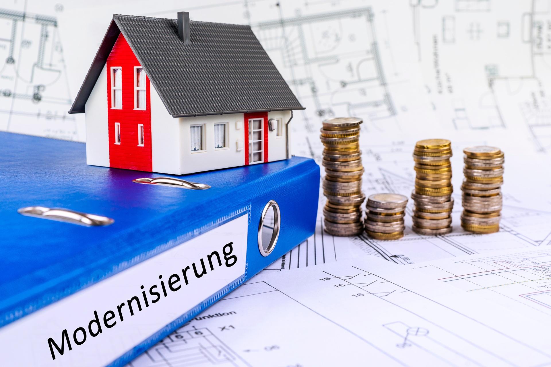 Hausmodell mit Geldstapeln auf Ordner Modernisierung | Gründach